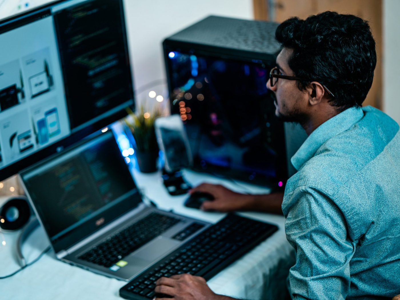 Engineer working at a multi-screen workstation with code and design drawings