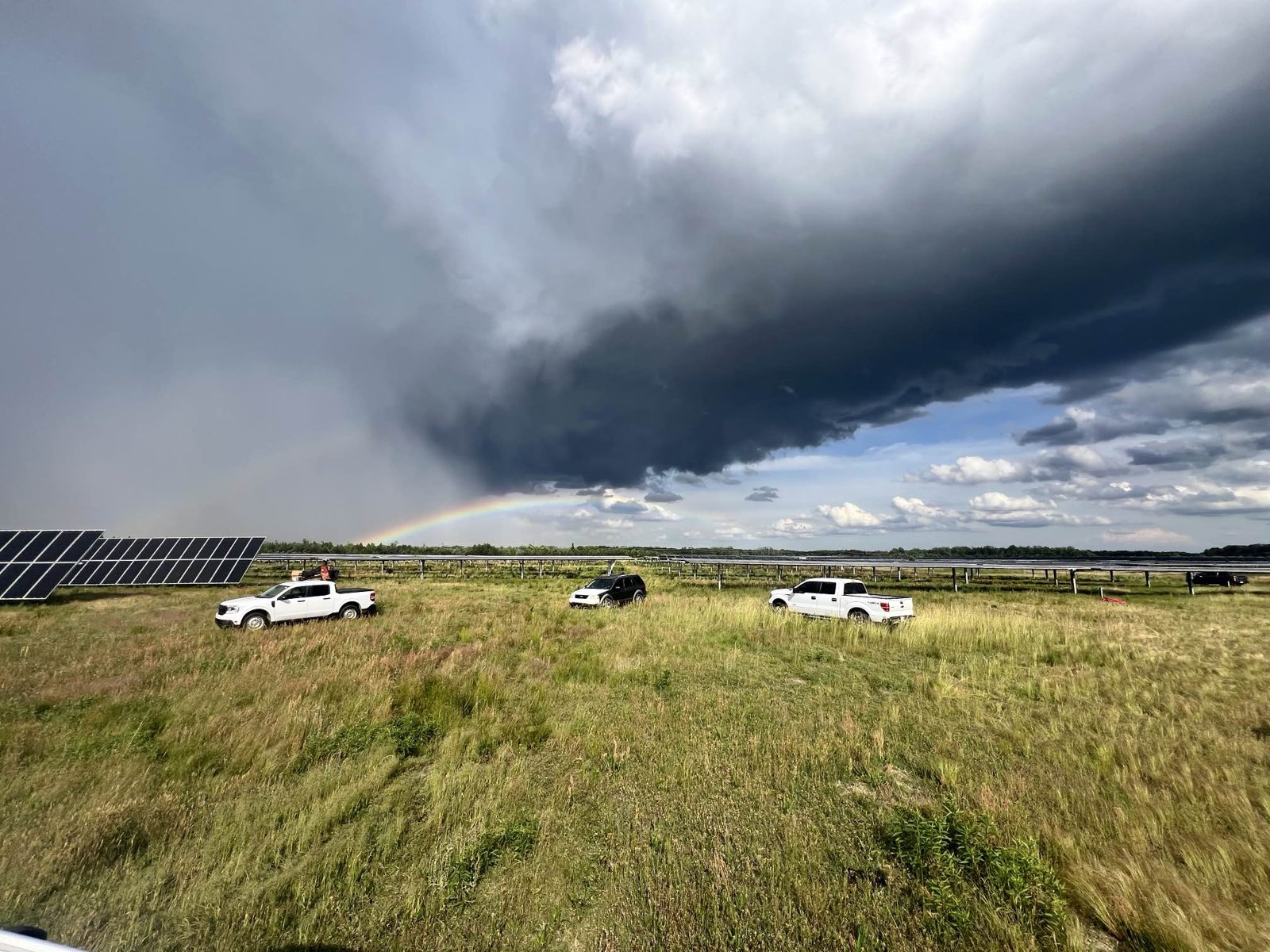 Crew trucks on site under a rainbow