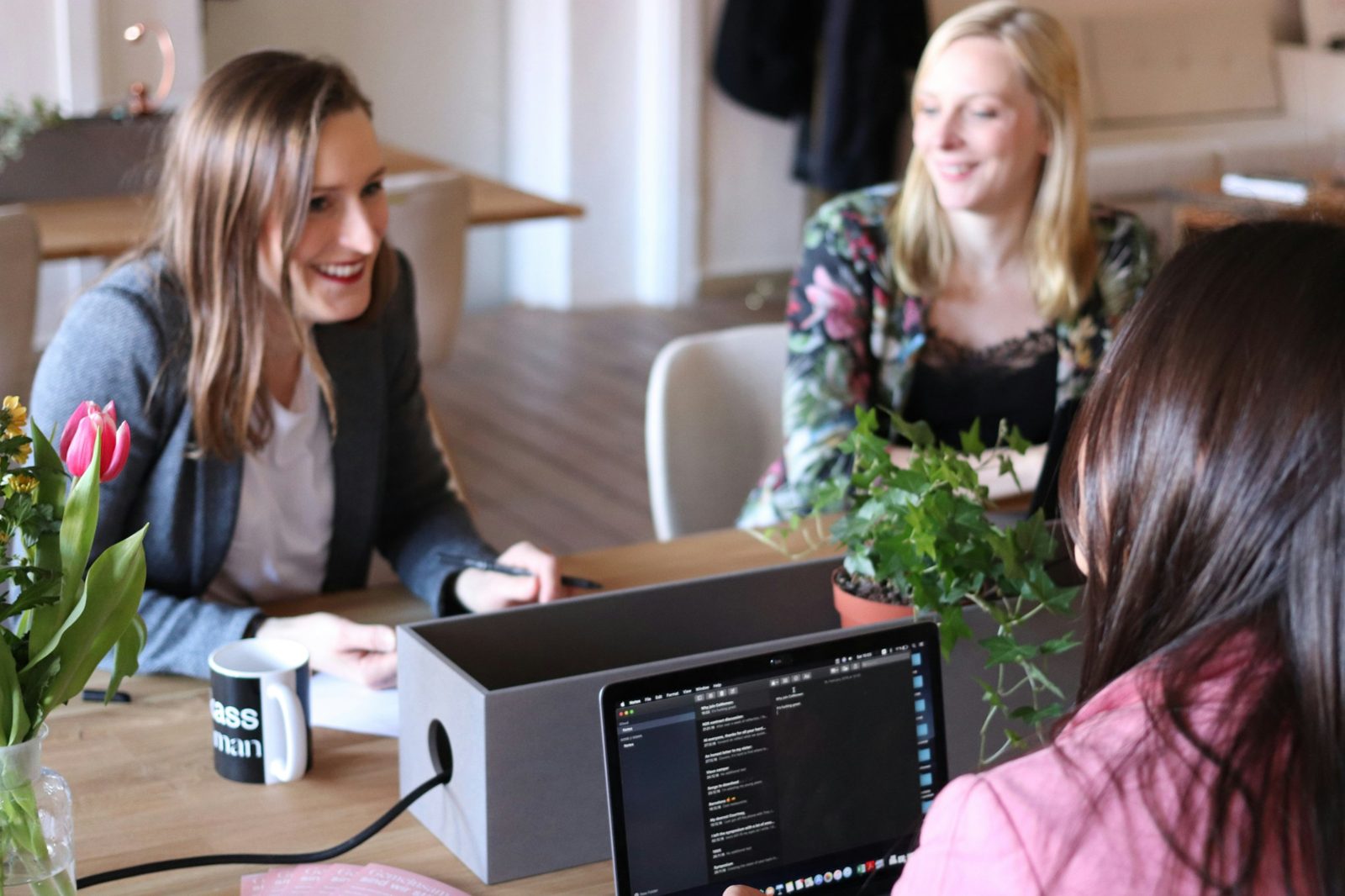 Colleagues smiling and talking around a table in a bright office