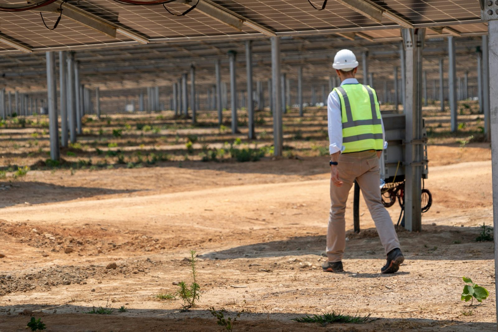 ACT technician in hard hat and safety vest walking beneath a solar array